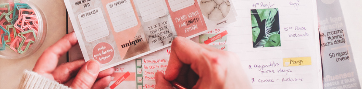 Žena piše u Inspire me planer i drži naljepnice u ruci