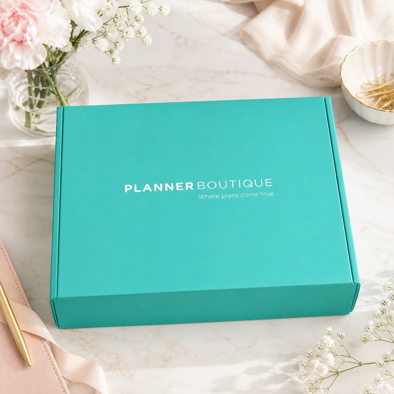 Tirkizna Planner Boutique kutija iznenađenja na elegantnom ženstvenom stolu, osvijetljena prirodnim svjetlom.